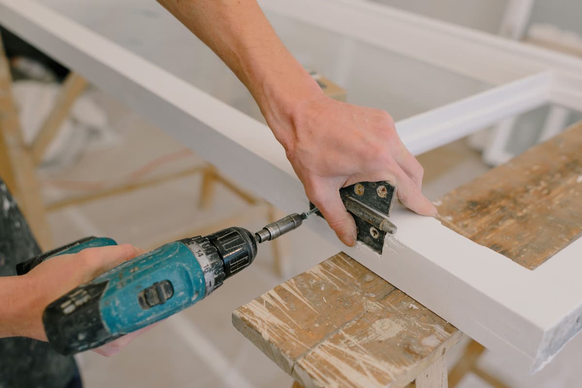 Carpenter fixing a hinge to a timber window frame