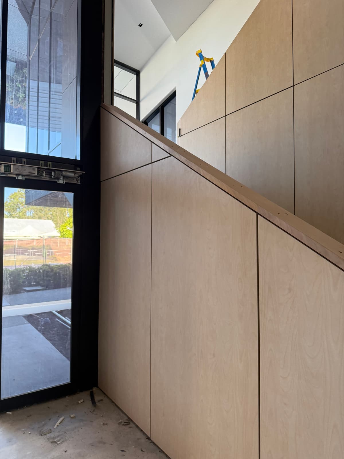 Timber veneer wall panelling and handrail beside a staircase, fitted by Hogan Projects